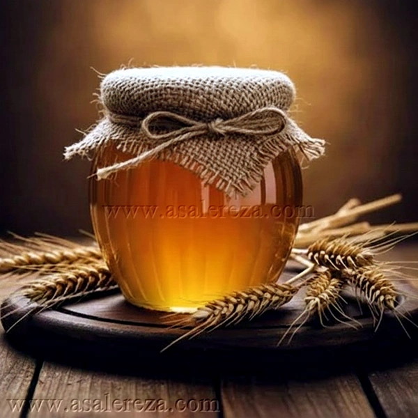 عسل گون در پت شیشه ای در میان خوشه های گندم روی میز چوبی